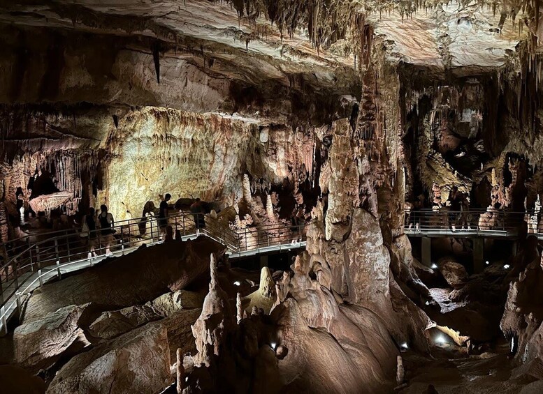 A cave with stalactites and stalagmites, a walkway, and visitors. 3