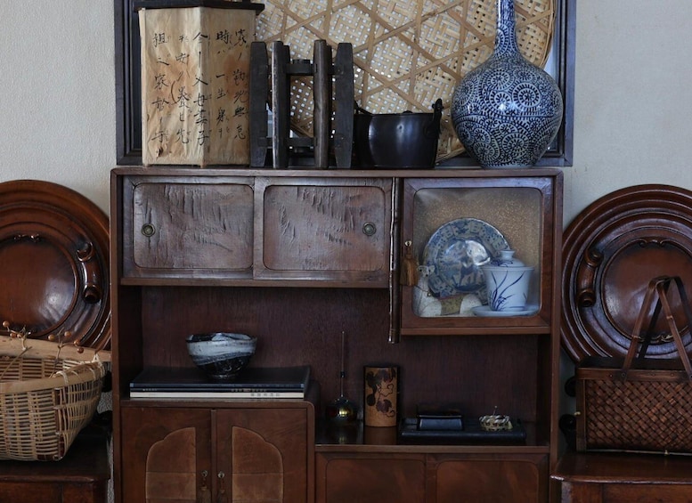 A wooden cabinet with decorative items including a vase, plates, and books. 3