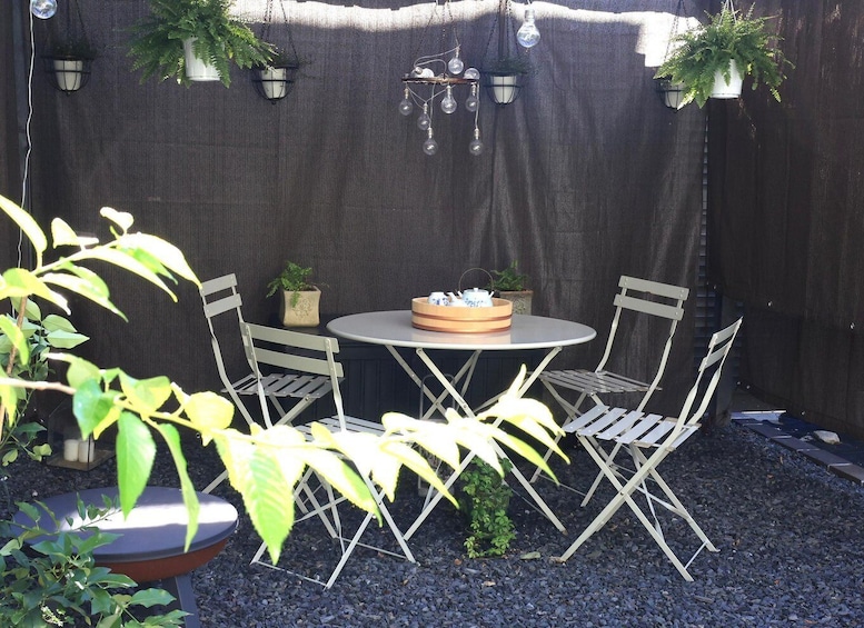 A patio with a round table, four chairs, hanging plants, and a lantern. 5