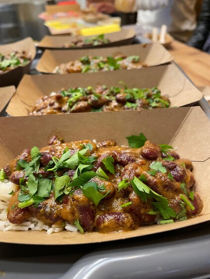 A meal with rice and a meat dish garnished with green herbs, served in a cardboard box. 1