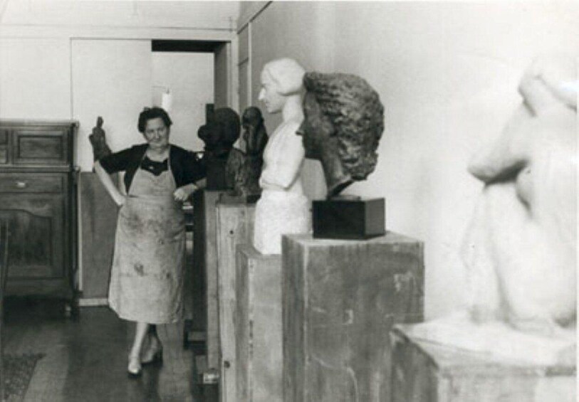 A person in an apron standing in a room with sculptures. 2