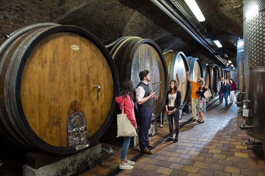 Una bodega con barriles de madera y visitantes. 2