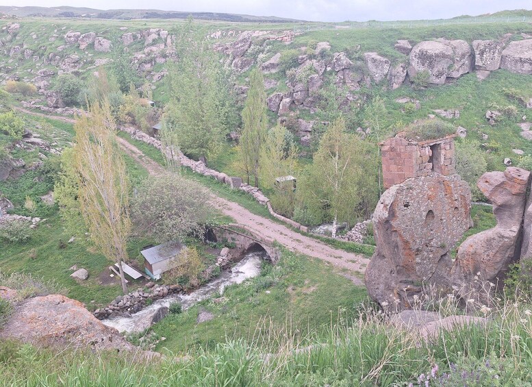 A rural landscape with a stone bridge, a small building, and a river. 5
