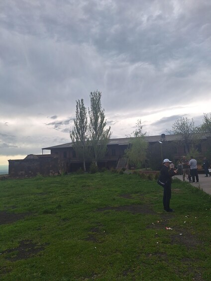 A grassy field with a building and trees in the background. 3