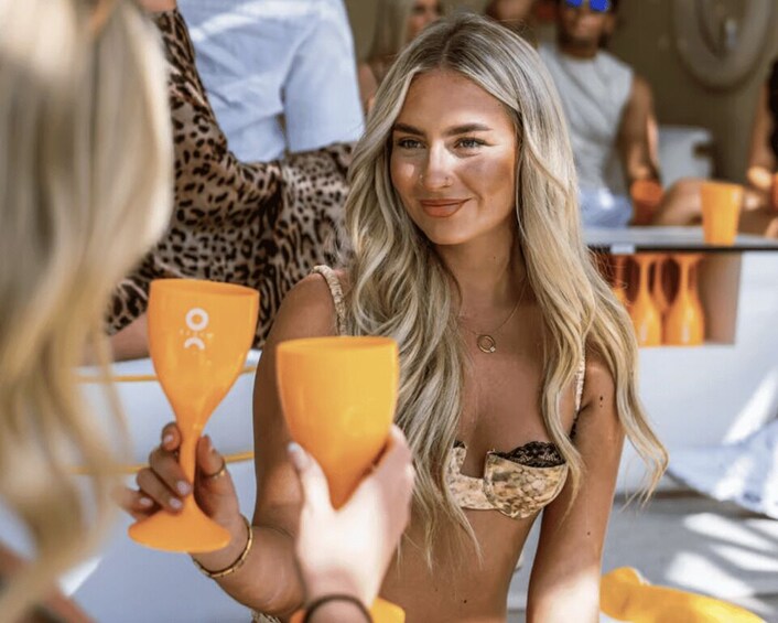 A person holding a glass with a logo, another person with a drink, and a leopard print garment in the background. 3