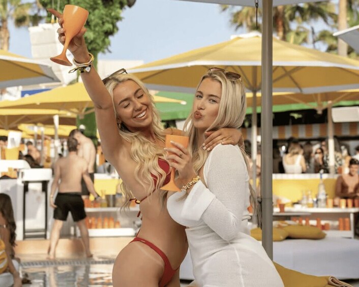 Two people at a poolside bar, one holding a drink. 1
