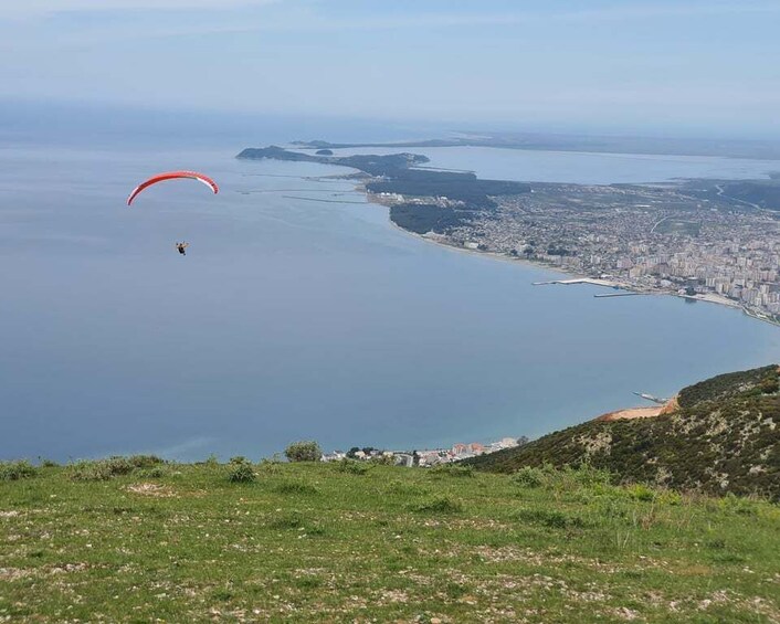 A paraglider over a coastal cityscape with a clear view of the coastline and urban area. 3