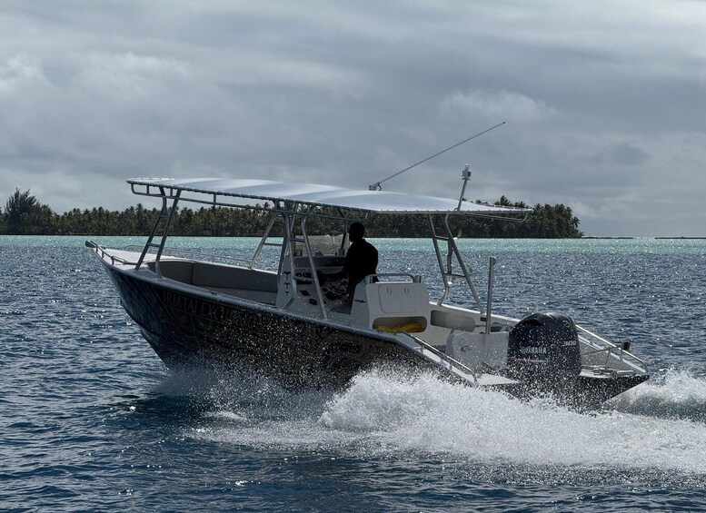 A boat moving through calm waters with a person steering, surrounded by a clear sky and distant land. 4
