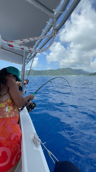 A person fishing on a boat with a clear view of the ocean and distant mountains. 2