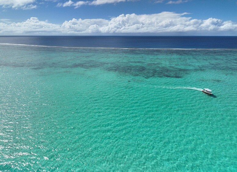 A boat on turquoise ocean waters with a clear sky and distant clouds. 3