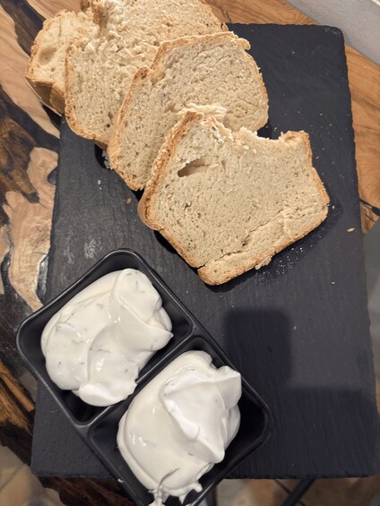 Sliced bread and a container of white spread on a slate board. 4