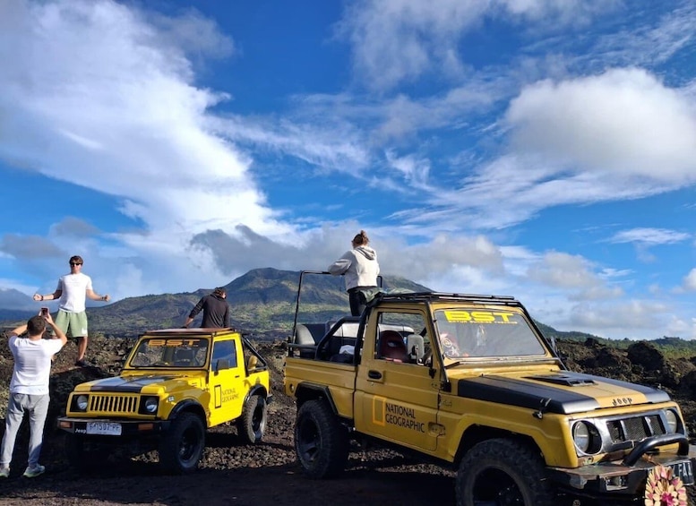 Two yellow off-road vehicles with 'National Geographic' branding parked on a rocky terrain with a mountainous backdrop. 4