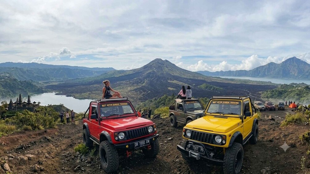 Two off-road vehicles parked on a dirt path with a mountainous landscape in the background. 2
