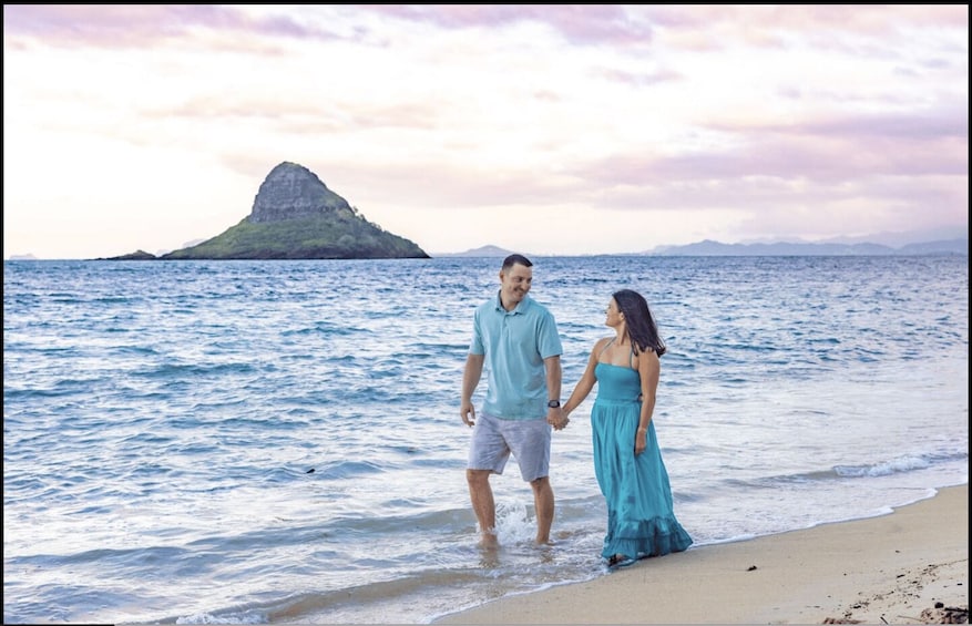 A couple walking on a beach with ocean and a distant island. 3