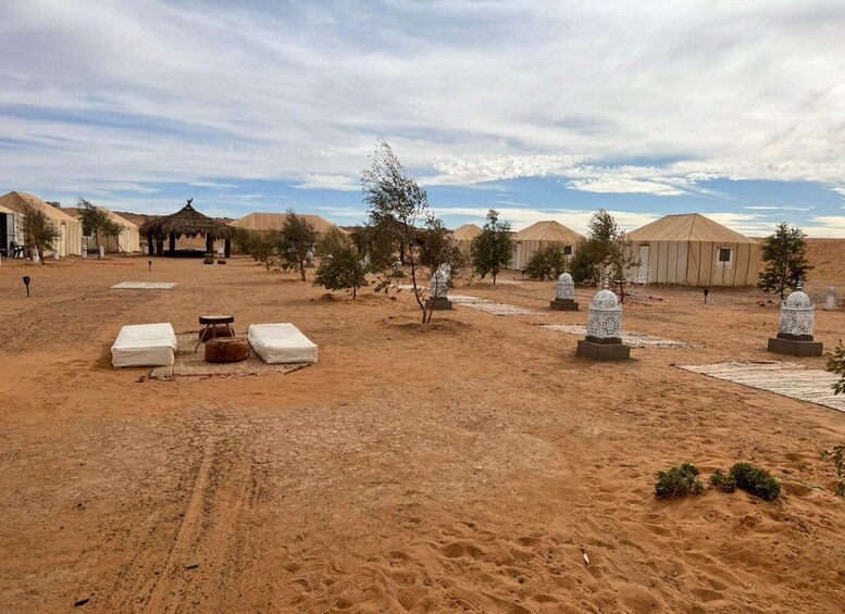 A desert landscape with yurts, white tents, and a few trees. 4