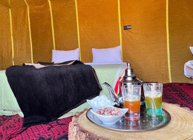 A tent interior with a bed, a tray with snacks, and drinks. 2