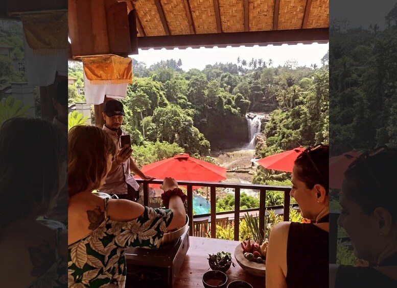 A group of people dining at a table with a view of a waterfall and lush greenery. 5