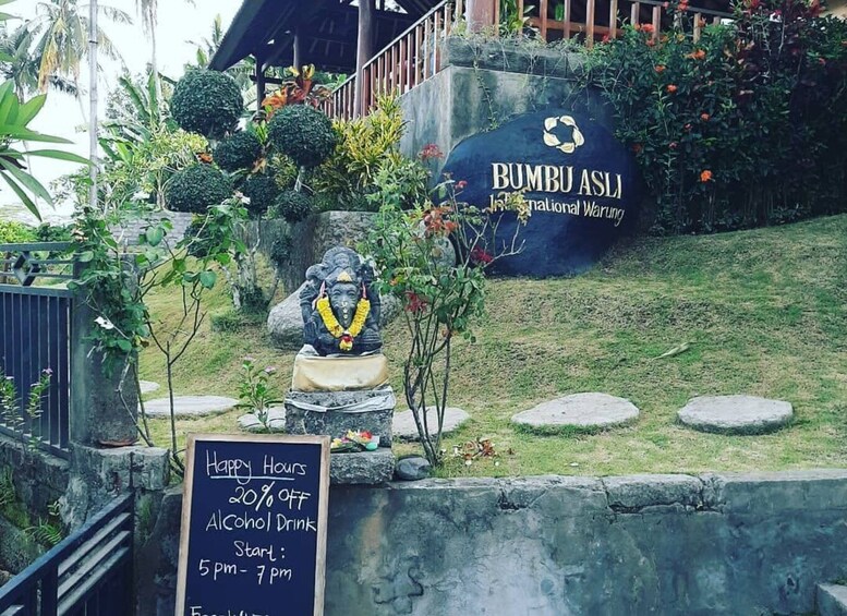 A Bumbu Asli sign with a statue and a Happy Hours sign. 2
