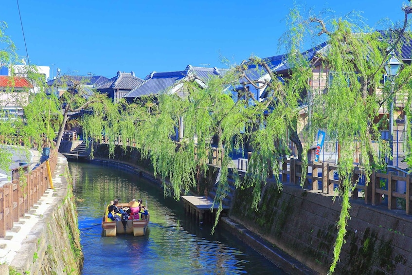 A narrow waterway with traditional buildings and willow trees lining the banks. 1