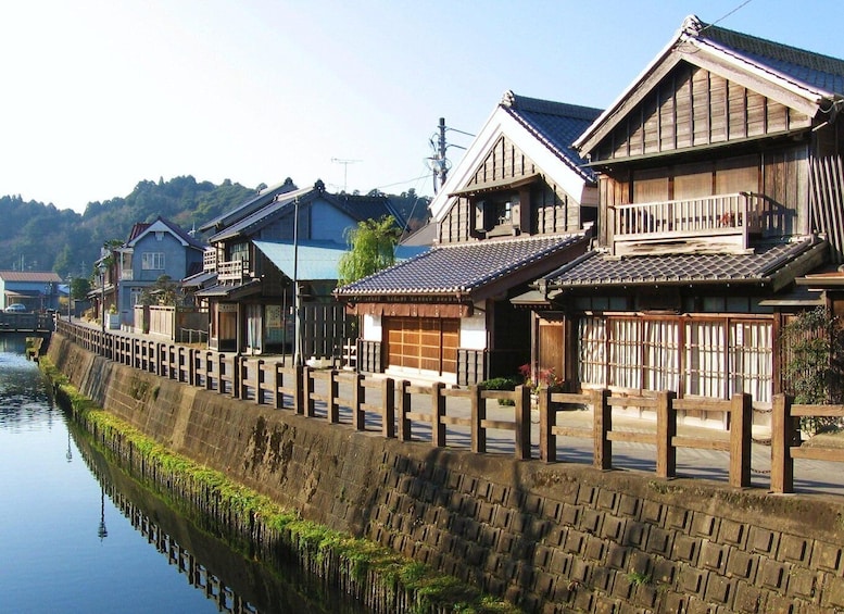 Traditional Japanese houses by a canal with a stone wall and wooden fences. 5