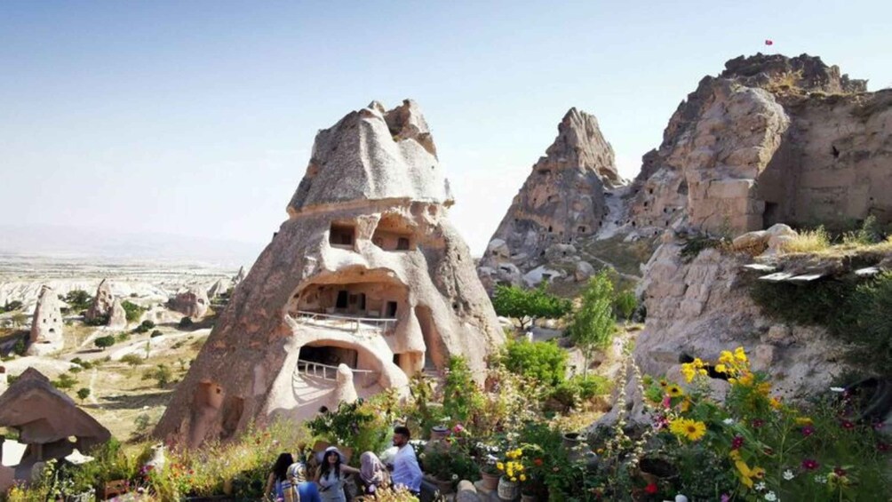 A rock formation with a cave-like structure, surrounded by greenery and other rock formations. 2