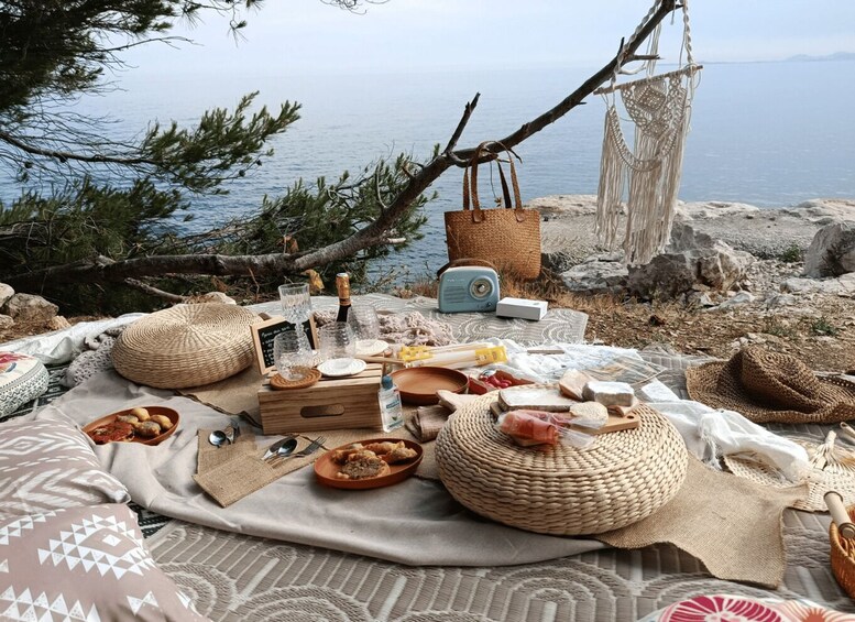 A picnic setup by a lakeside with a blanket, food, drinks, and a vintage radio. 4