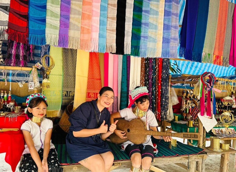A market stall with colorful fabrics, a guitar, and traditional jewelry. 1