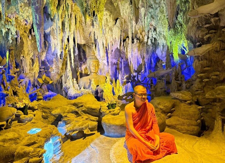A monk seated in a cave with stalactites and a Buddha statue. 2