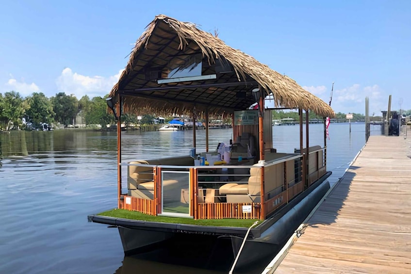 A boat with a thatched roof docked at a wooden pier. 1