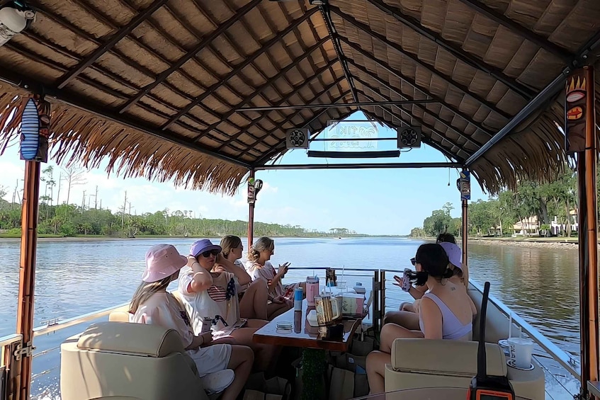 A group of people on a boat with a thatched roof, looking at the water. 4