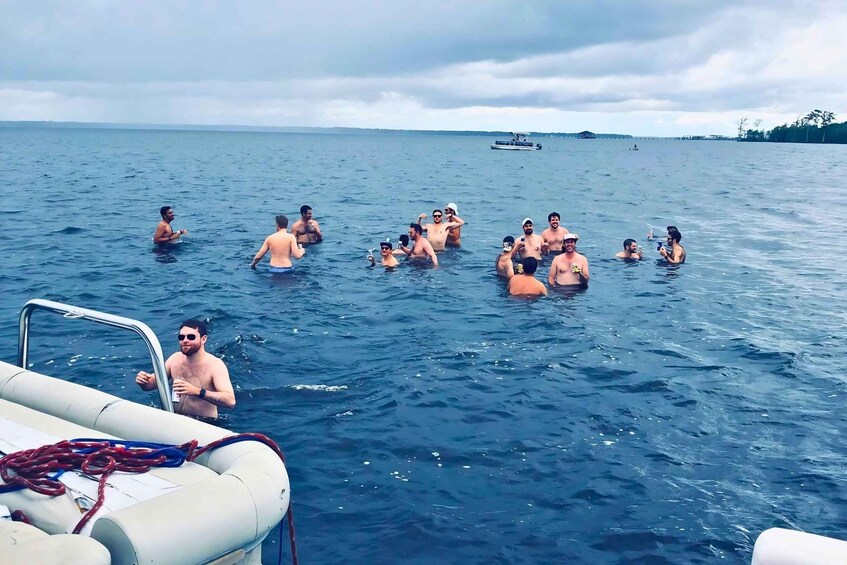 A group of people swimming in the ocean with a boat in the background. 3