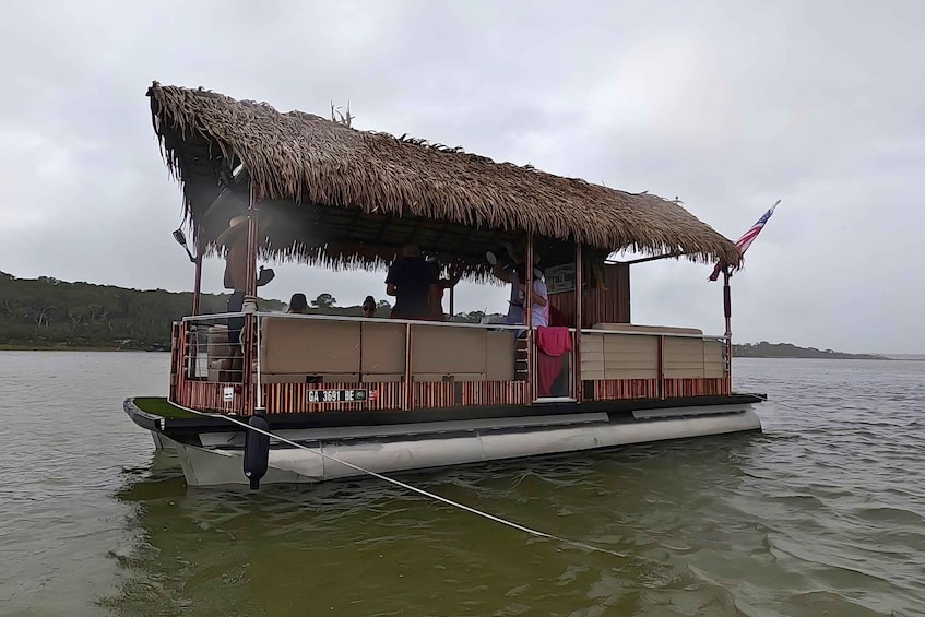 A stationary boat with a thatched roof and an American flag, floating on calm water. 5
