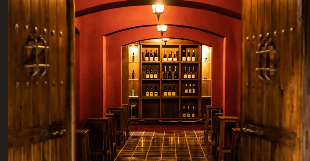 A wine cellar with wooden doors and shelves of wine bottles. 1