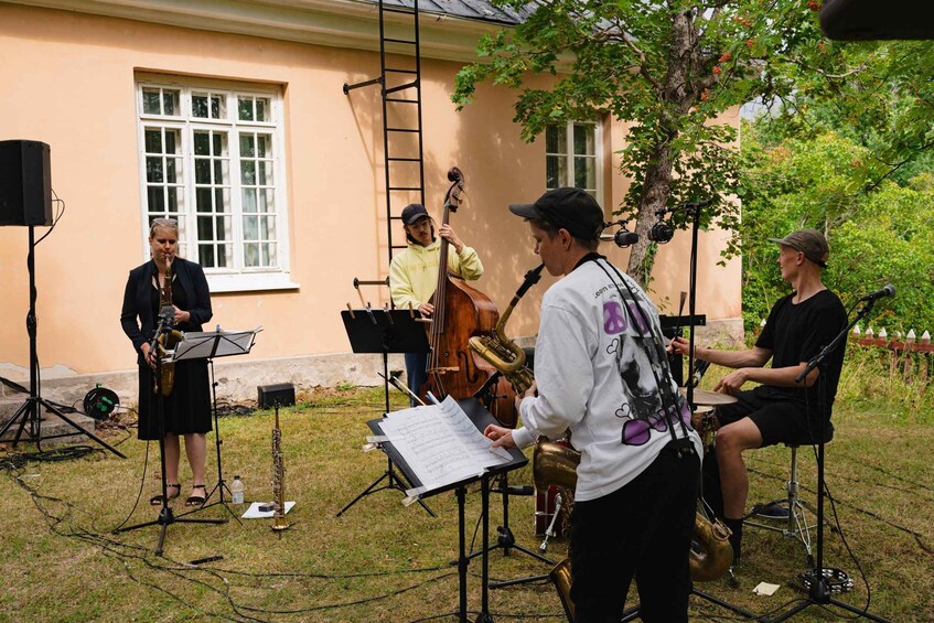 A brass band performing outdoors with sheet music, brass instruments, and a microphone stand. 4