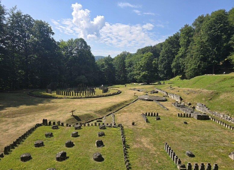 A historical site with stone structures and mounds, surrounded by trees. 3