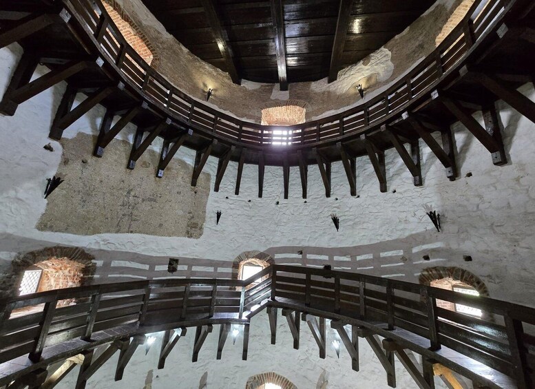 A circular stone structure with wooden beams and a central light fixture. 2