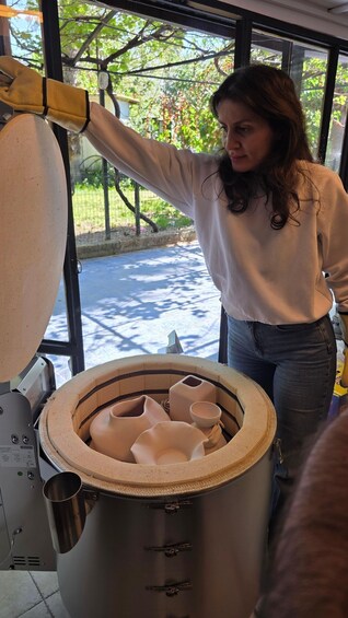 A person operating a pottery wheel, with clay pieces and tools inside the wheel. 4