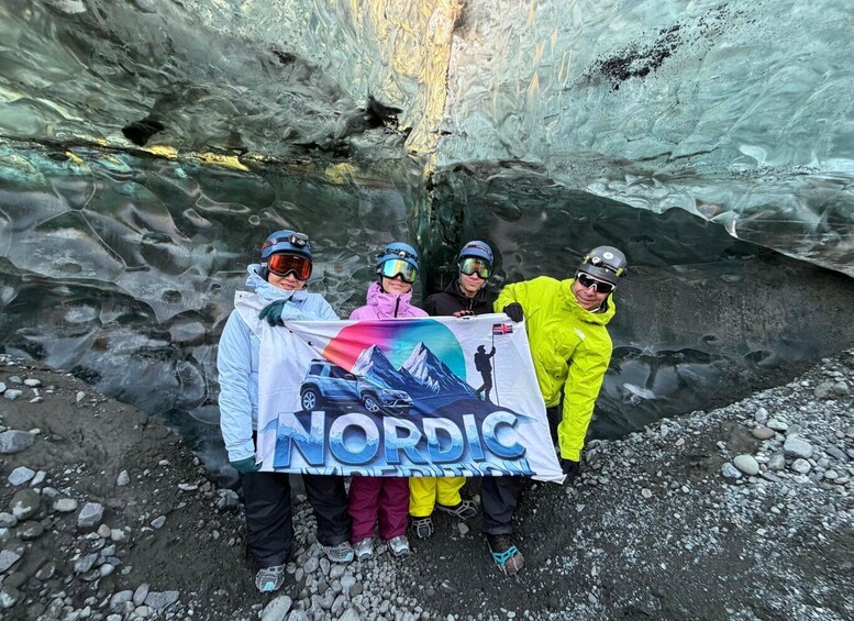 Four people holding a banner with a Nordic theme, standing in front of a glacier. 4