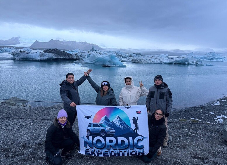A group of people posing with a banner in front of a glacier. 2