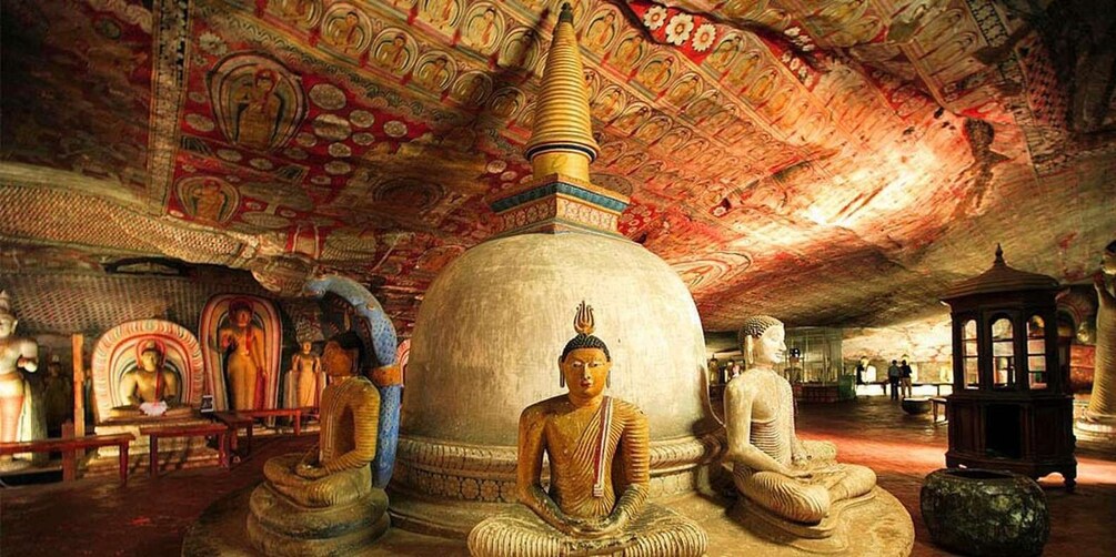 A temple interior with large Buddha statues, intricate ceiling artwork, and a prominent stupa. 3