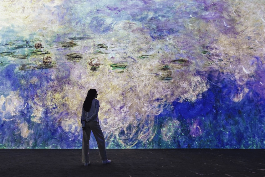 A person standing in front of a large abstract painting with swirling patterns and colors. 1