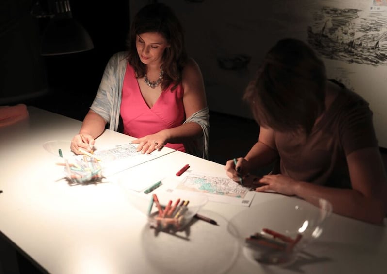 Two people drawing at a table with colored pencils. 2