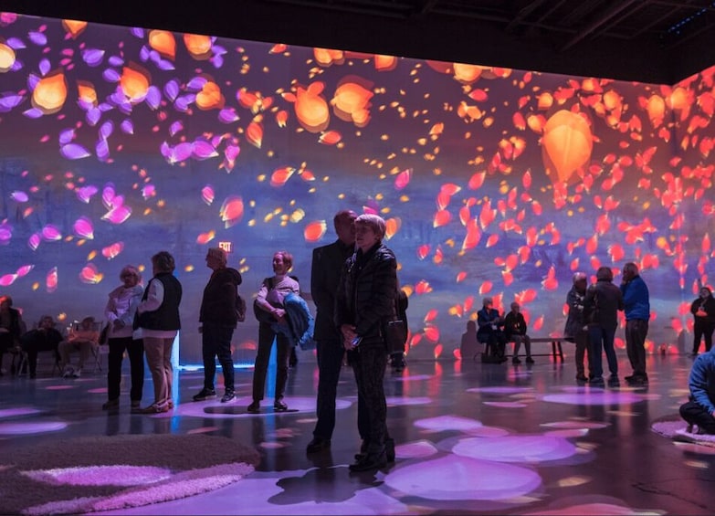 A group of people in an indoor setting with a large screen displaying floating lanterns. 5