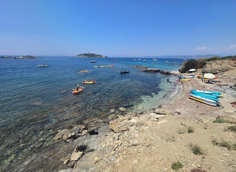 A rocky shoreline with kayaks and a lighthouse in the distance. 1