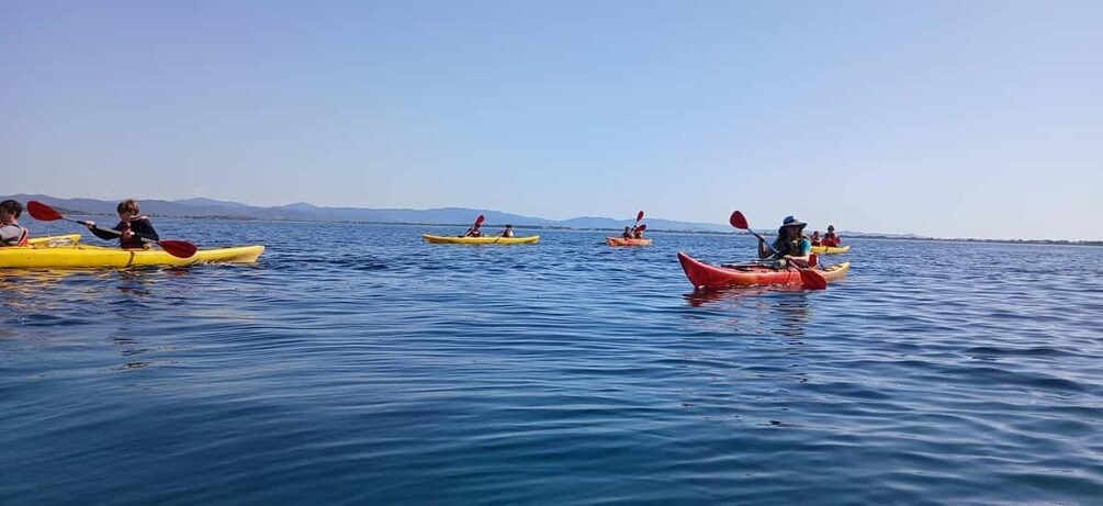 People kayaking on a calm sea with clear skies. 3