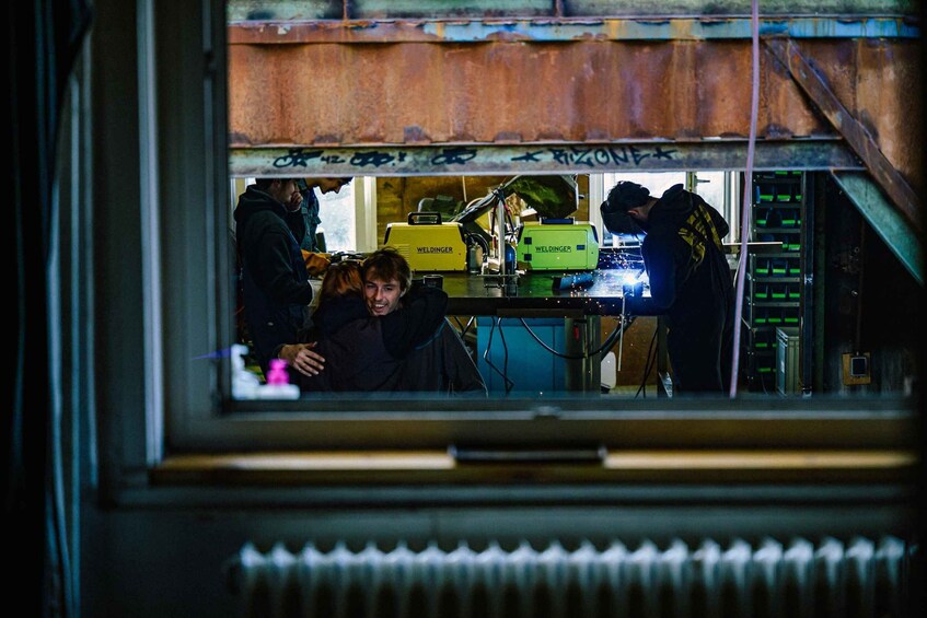 A window view of a workshop with welding equipment and a person working. 3