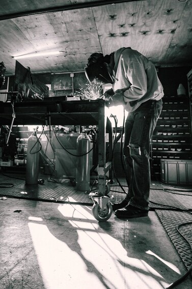 A person welding in a workshop with metal structures and welding equipment. 4