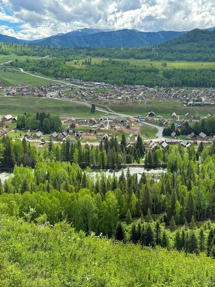 A rural village with houses, a river, and mountains in the background. 5