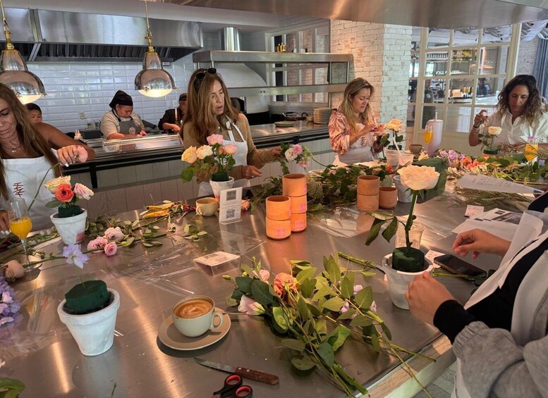 A group of people in a kitchen setting, some holding flowers and others working at the counter. 4