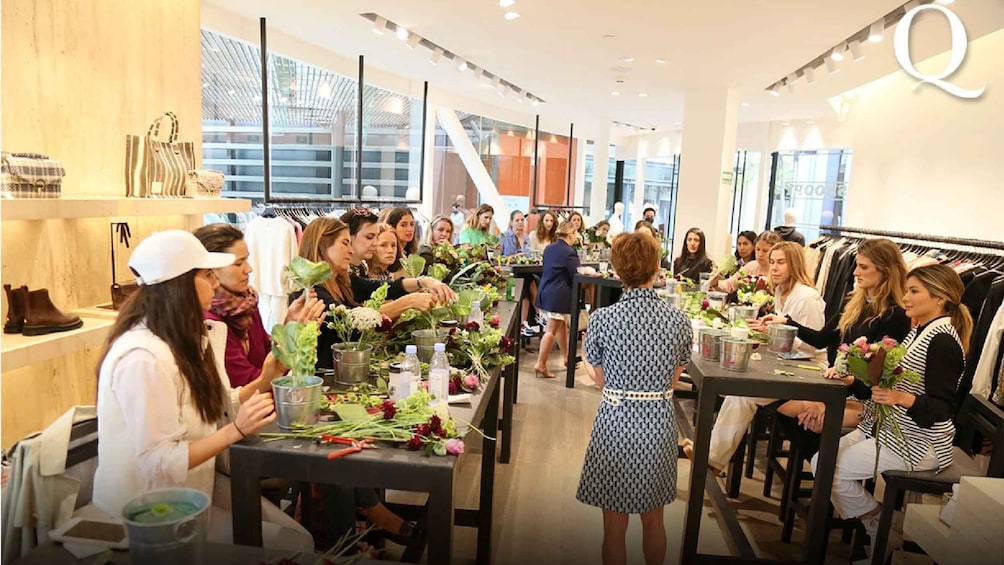 A group of people dining in a modern restaurant with tables set with flowers and drinks. 1